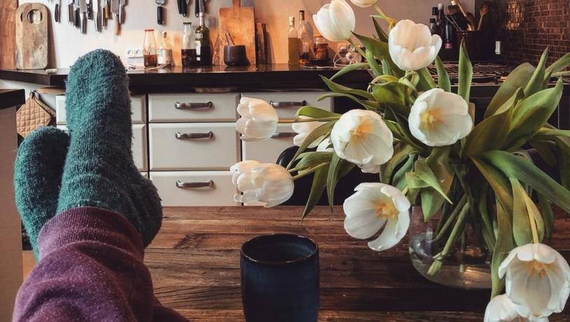 Persona che si distende in una cucina accogliente che indossa calzini di lana. Scopri qual è la parola danese Hygge