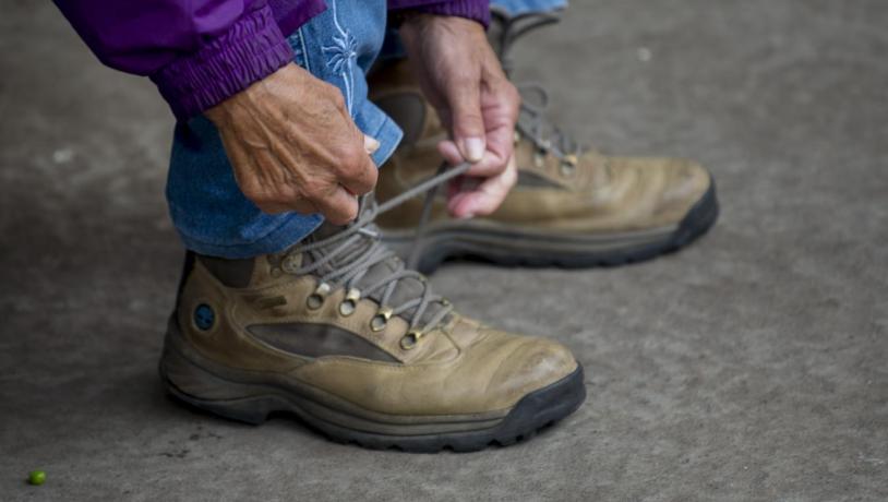 Wanderer schnürt Wanderschuhe auf dem dänischen Pilgerweg Heerweg