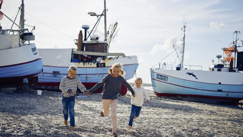 Tre barn som løper på Thorup strand i Nordjylland