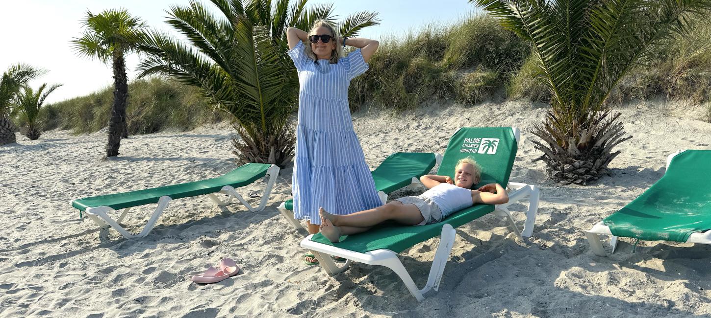 Lisa står på palmstranden och hennes dotter ligger på solstol