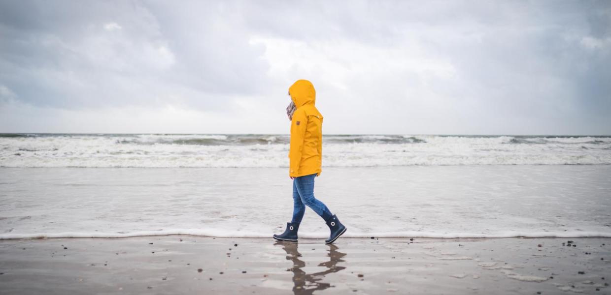 Spaziergänger in gelber Regenjacke am Strand von Blåvand an der Dänischen Nordsee