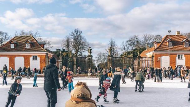 Barn og voksne står på skøyter utenfor Frederiksberg Have i København