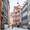 A woman cycles down snowy Magstræde in Copenhagen, Denmark