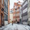 A woman cycles down snowy Magstræde in Copenhagen, Denmark