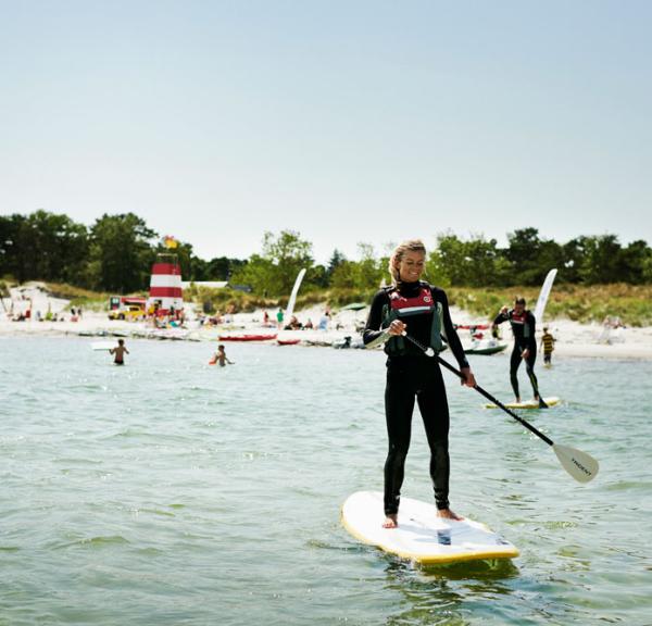 A woman rides a paddleboard - SUP - in Bornholm, Denmark