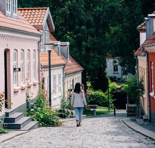 kvinne som går nedover brosteinsgate i Odense 