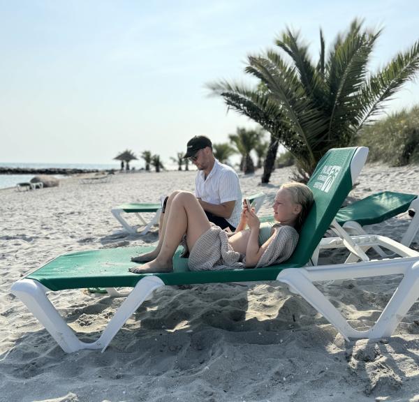 En man och ett bar ligger på solstolar på palmstranden i Jylland